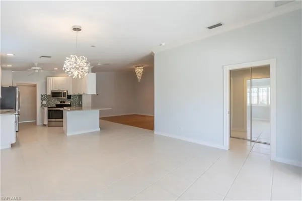 a view of a kitchen with granite countertop a refrigerator and a chandelier
