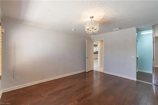 an empty room with wooden floor and chandelier
