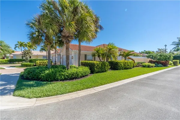 a front view of a house with a yard and palm trees