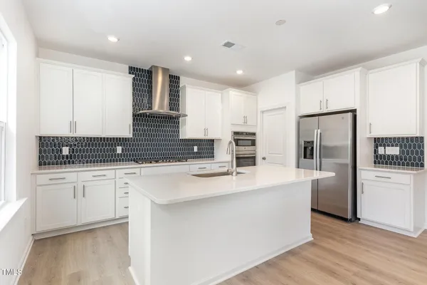 a large kitchen with stainless steel appliances lots of counter space and wooden floor