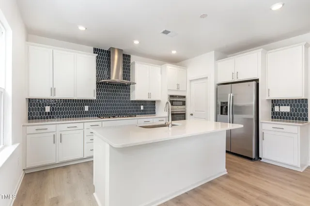 a large kitchen with stainless steel appliances lots of counter space and wooden floor