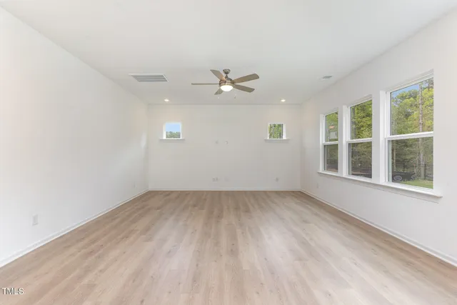 an empty room with a window and a ceiling fan