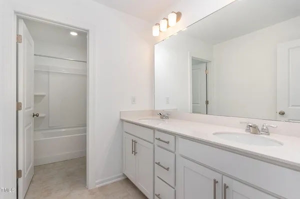 a bathroom with a double vanity sink a mirror and a bathtub