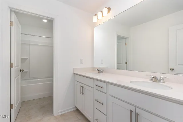 a bathroom with a double vanity sink a mirror and a bathtub