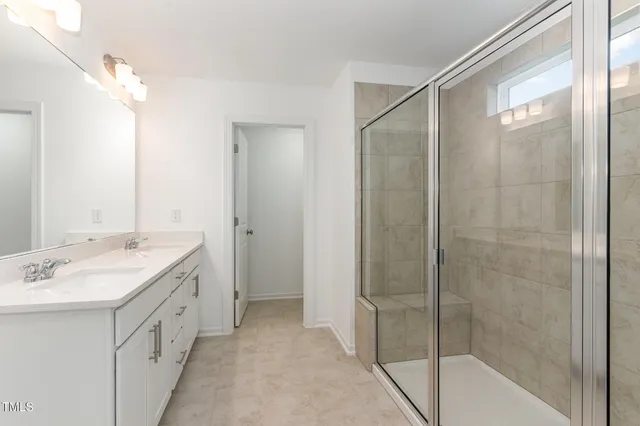 a spacious bathroom with a double vanity sink a large mirror and shower