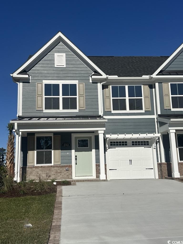 View of front of property featuring covered porch, concrete driveway, and a garage