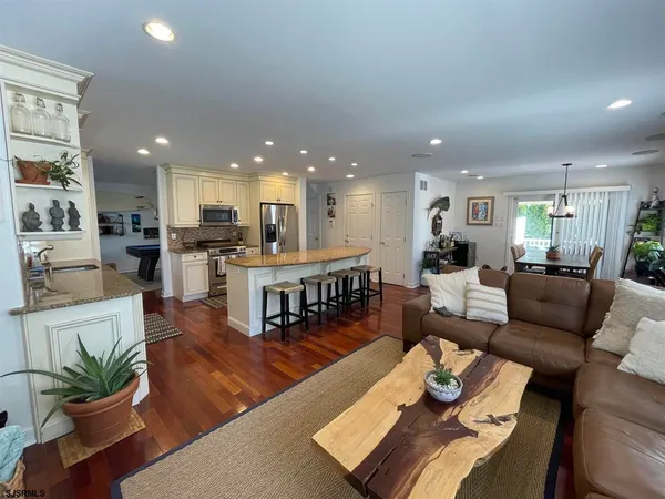 a living room with furniture kitchen view and a wooden floor