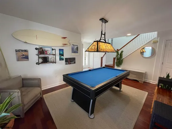 a room with wooden floor pool table and a couch