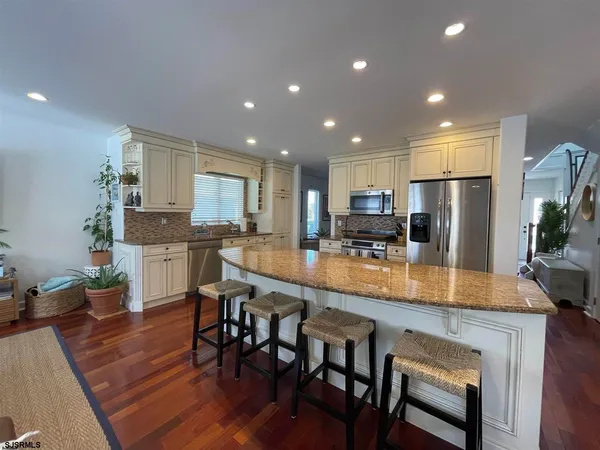 a kitchen with stainless steel appliances granite countertop table chairs refrigerator and microwave