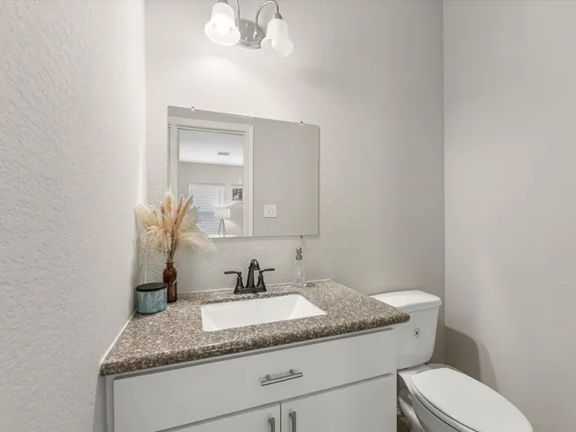a bathroom with a granite countertop sink a toilet and a mirror