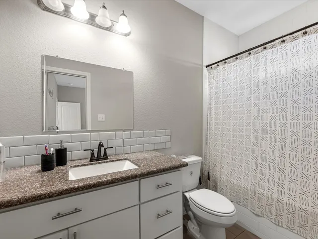 a bathroom with a granite countertop sink a toilet and mirror