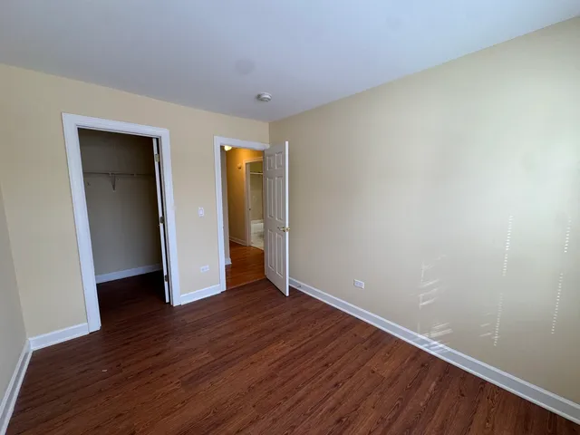 a view of an empty room with wooden floor and closet