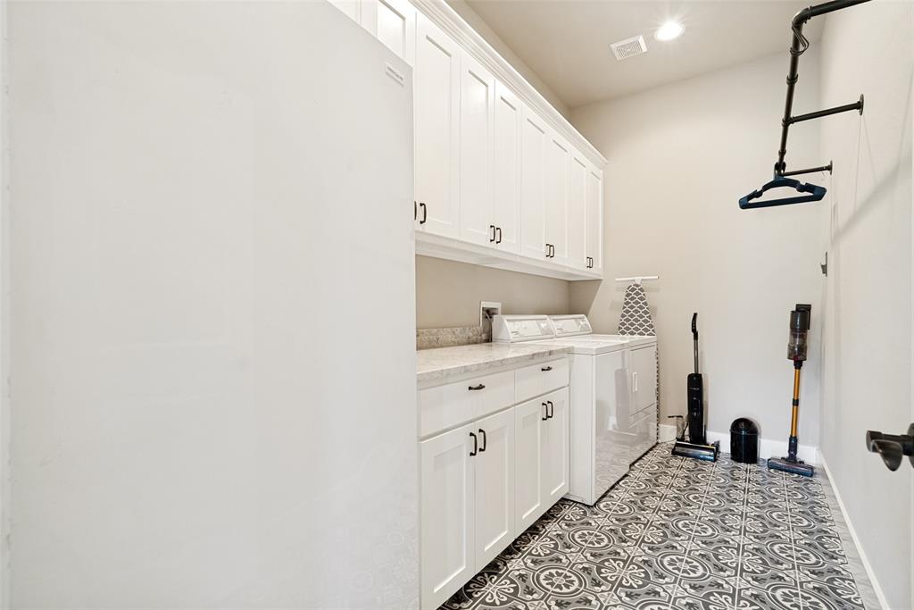6913 Veal Station Road Weatherford, TX 76085 - Photo 24 of 31 Dedicated utility room featuring patterned floor tile, white shaker cabinetry with dark hardware, stone-finish countertops, and a built-in wall-mounted clothes rack