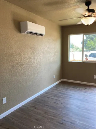 a view of an empty room with a window and wooden floor