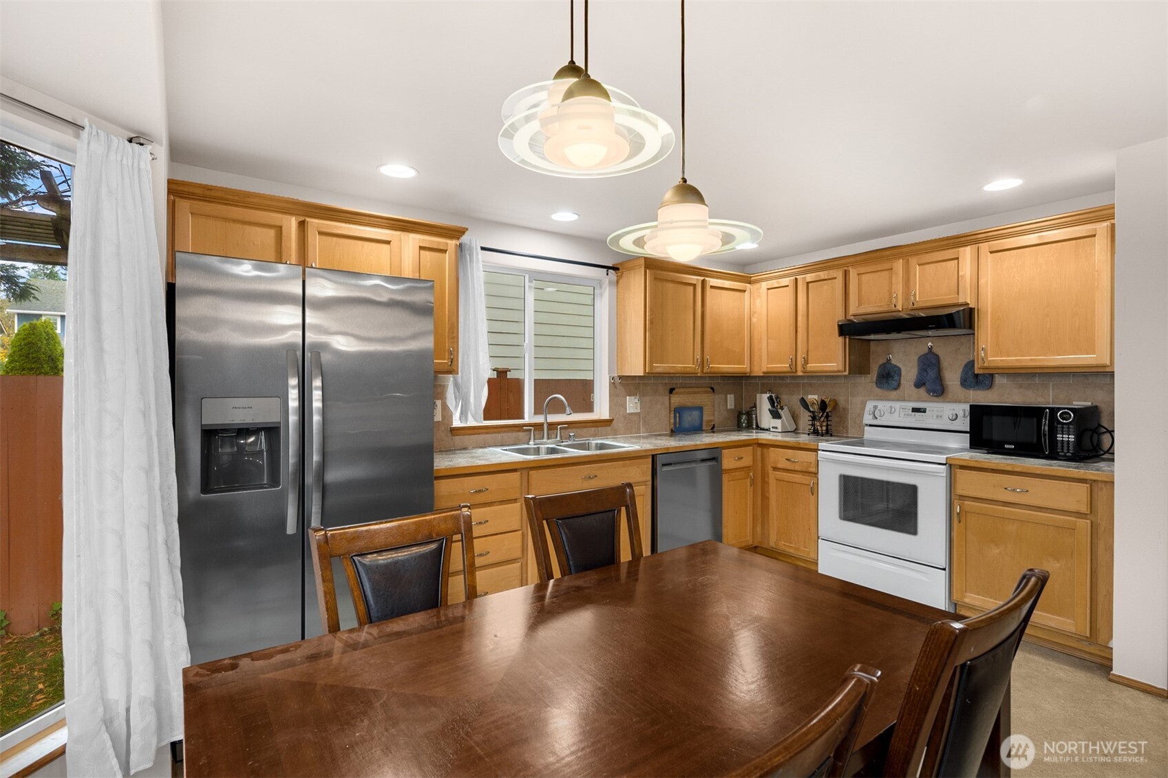 2632 Northeast 24th Court Renton, WA 98056 - Photo 3 of 33 a kitchen with stainless steel appliances granite countertop a stove a sink a refrigerator a microwave oven with a dining table and chairs
