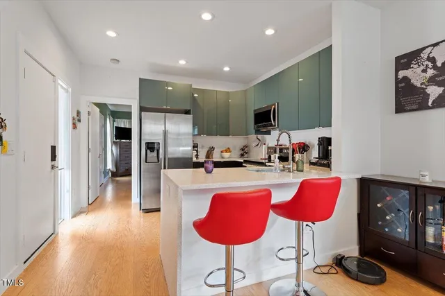 a kitchen with stainless steel appliances granite countertop a refrigerator a stove a sink dishwasher and a dining table with wooden floor