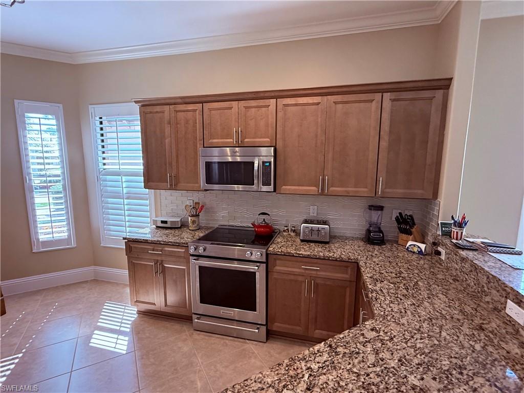 7543 Moorgate Point Way Naples, FL 34113 - Photo 16 of 31 a kitchen with stainless steel appliances a stove a sink and a microwave