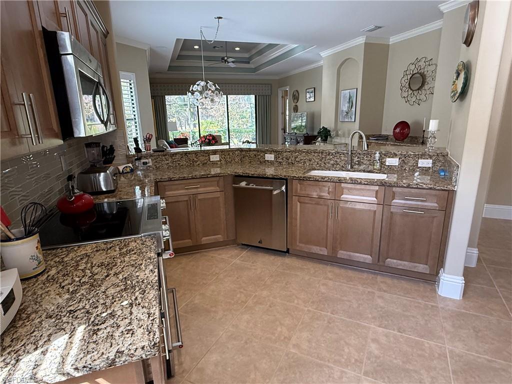 7543 Moorgate Point Way Naples, FL 34113 - Photo 18 of 31 a kitchen with stainless steel appliances granite countertop a sink stove and cabinets