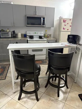 a kitchen with a stove a sink and chairs