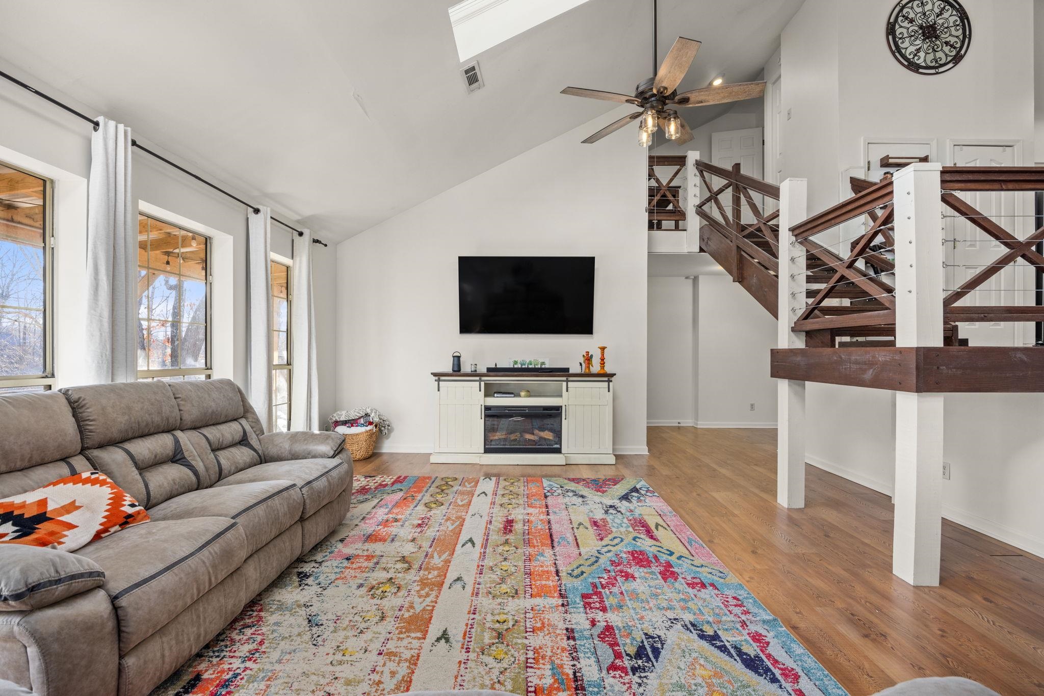 Living room featuring high vaulted ceiling, light hardwood / wood-style floors, and ceiling fan