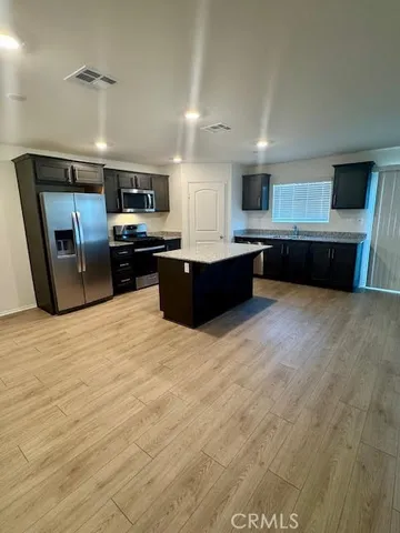 a large kitchen with stainless steel appliances kitchen island granite countertop a table and chairs in it
