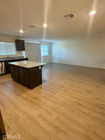 a view of kitchen and empty room with wooden floor