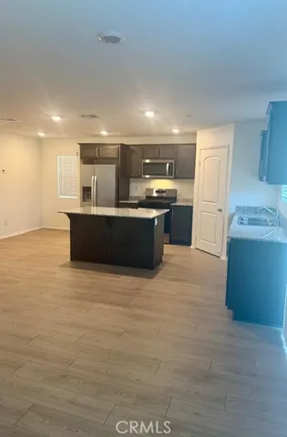 a large kitchen with stainless steel appliances a large counter top a stove and a refrigerator