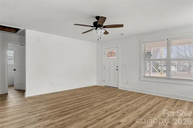a view of empty room with wooden floor and ceiling fan