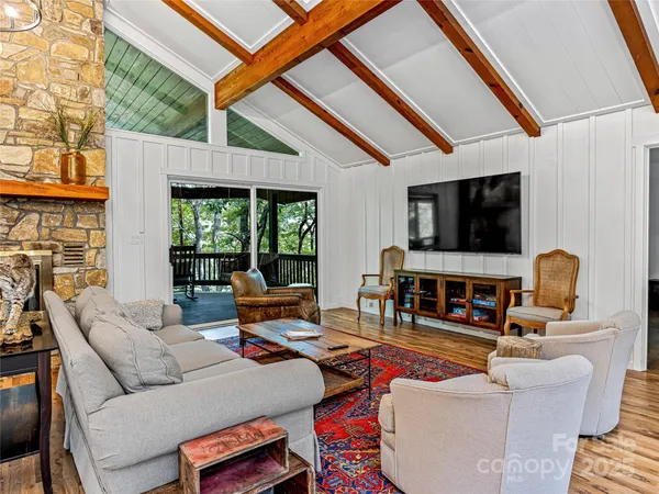 a living room with furniture a flat screen tv and a floor to ceiling window