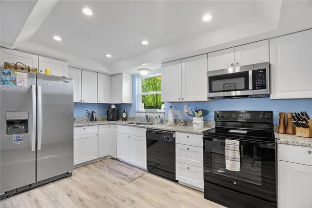 a kitchen with granite countertop a refrigerator stove and microwave