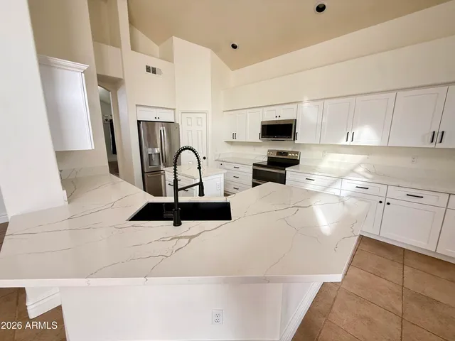 a kitchen with stainless steel appliances a stove a refrigerator a sink a microwave and white cabinets