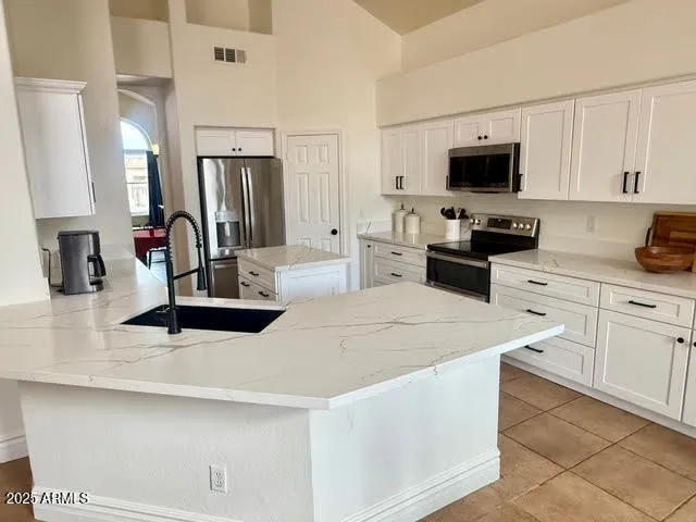 a kitchen with stainless steel appliances white cabinets a sink and a stove