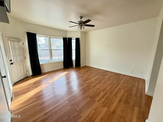 a view of empty room with wooden floor and fan