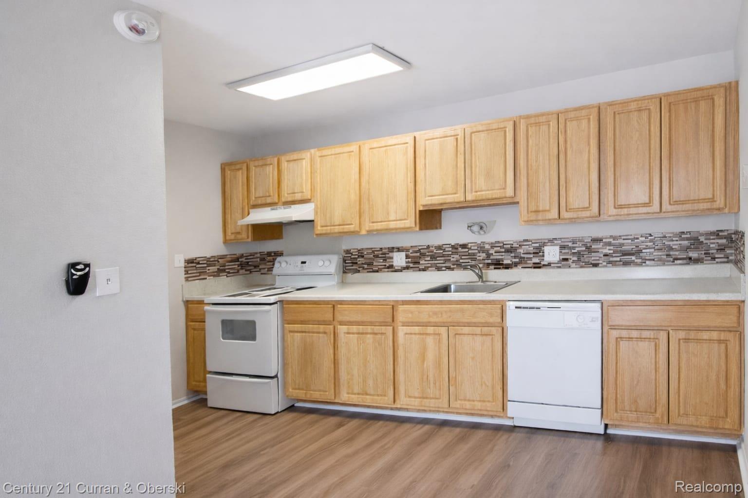 6015 Southfield Road, Unit 6 Detroit, MI 48228 - Photo 6 of 10 Kitchen featuring white appliances, light wood finish cabinetry, light countertops, and tasteful backsplash