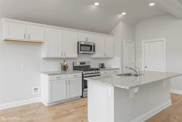 a kitchen with stainless steel appliances granite countertop a sink stove and cabinets