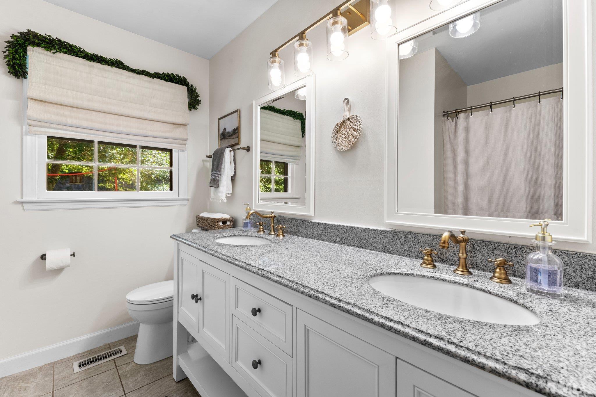 6704 Valley Drive Raleigh, NC 27612 - Photo 26 of 39 a bathroom with a granite countertop double vanity sink a mirror and a toilet