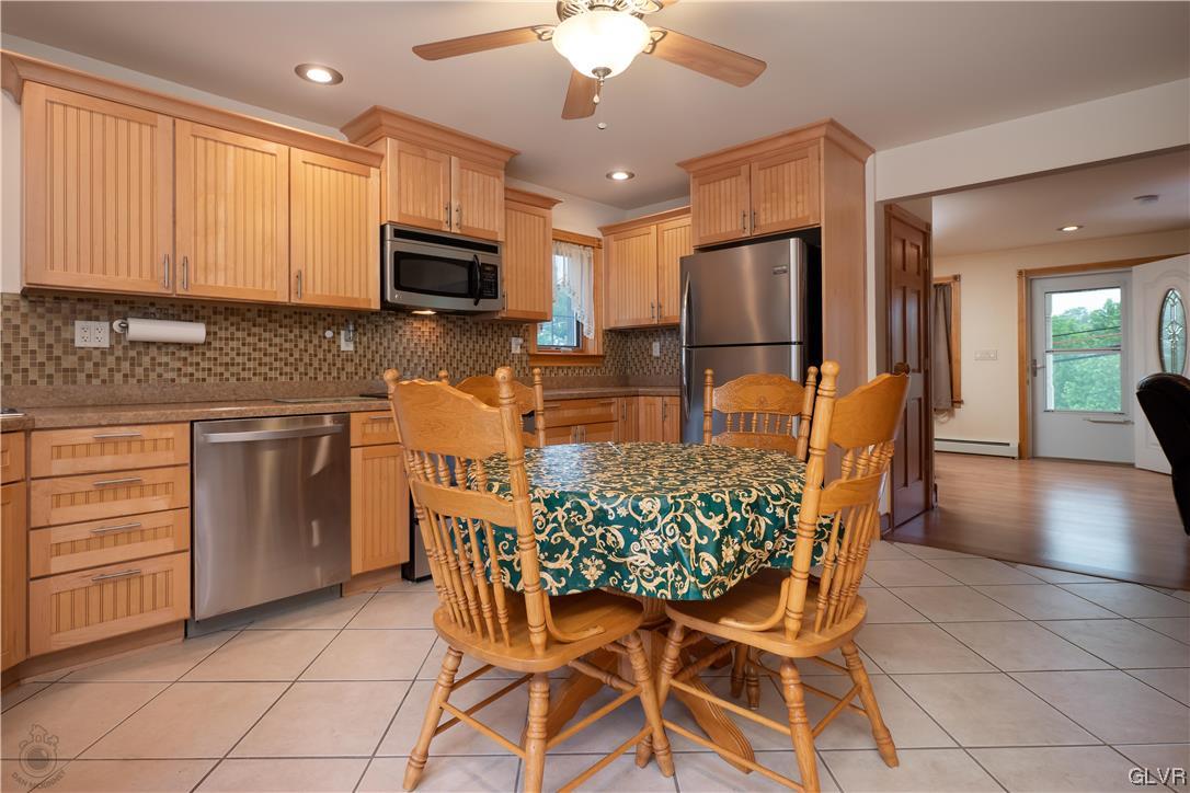 2174 Blue Barn Road Orefield, PA 18069 - Photo 5 of 23 a kitchen with stainless steel appliances granite countertop a stove top oven a sink dishwasher a dining table and chairs with wooden floor