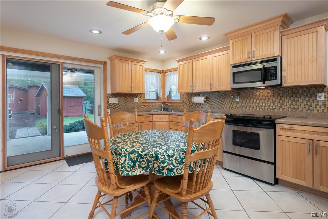 2174 Blue Barn Road Orefield, PA 18069 - Photo 6 of 23 a kitchen with stainless steel appliances granite countertop a stove top oven a sink dishwasher a dining table and chairs with wooden floor