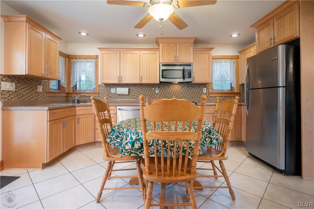 2174 Blue Barn Road Orefield, PA 18069 - Photo 7 of 23 a kitchen with stainless steel appliances a refrigerator a stove a sink a dining table and chairs
