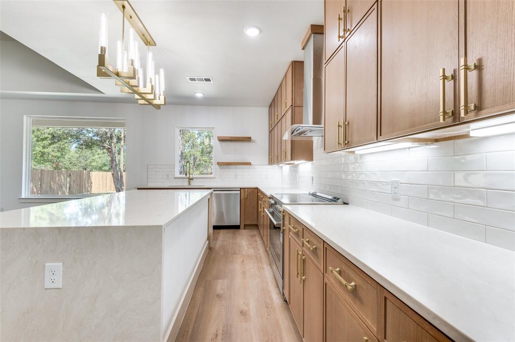 3913 Blue Ridge Boulevard Dallas, TX 75233 - Photo 12 of 25 Spacious kitchen featuring an extended island, light wood-finish cabinetry with brass hardware, white subway tile backsplash, and stainless steel appliances