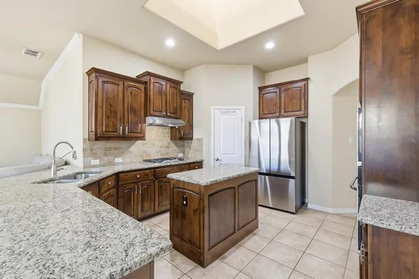 a kitchen with stainless steel appliances kitchen island granite countertop a sink and refrigerator