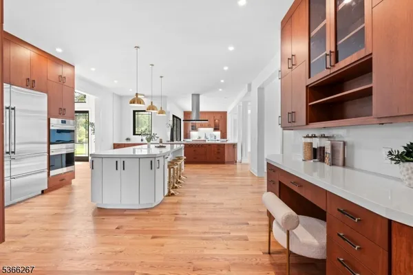 a kitchen with stainless steel appliances kitchen island granite countertop a table chairs and a wooden floor
