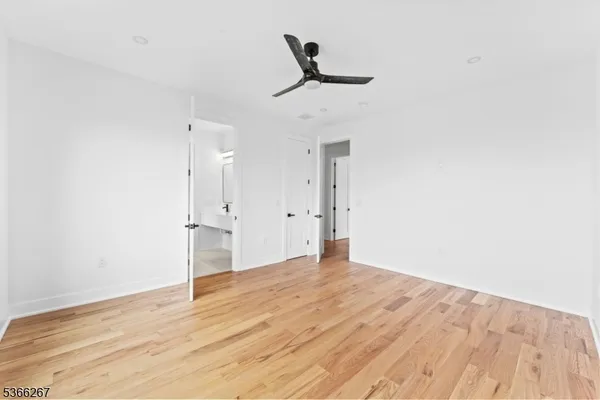 a view of empty room with wooden floor and ceiling fan