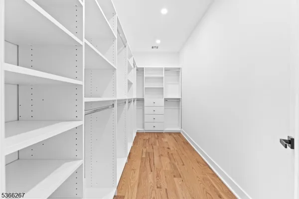 a view of a hallway with white cabinets and wooden floor