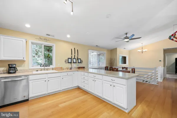 a large white kitchen with a stove a sink a window and dining table