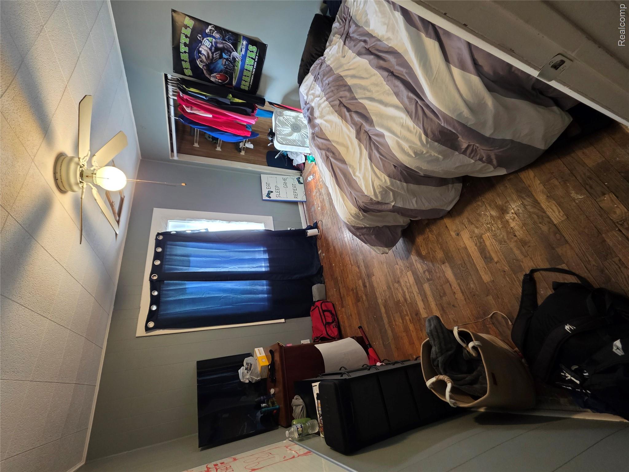 4217 Pengelly Road Flint, MI 48507 - Photo 21 of 26 Room featuring wood-finish flooring, a window with dark curtains, and a ceiling fan with integrated lighting