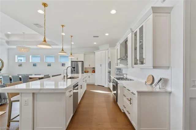 a large white kitchen with stainless steel appliances lots of counter space and a sink