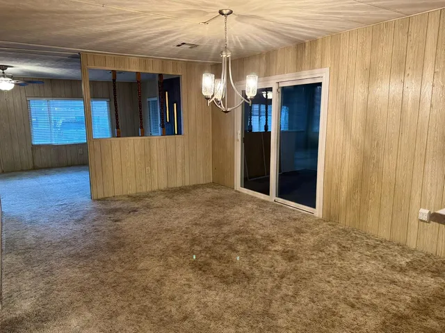 a view of a hallway with wooden floors and chandelier