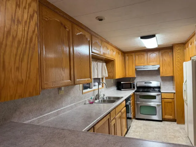a kitchen with stainless steel appliances granite countertop a stove a sink and a refrigerator