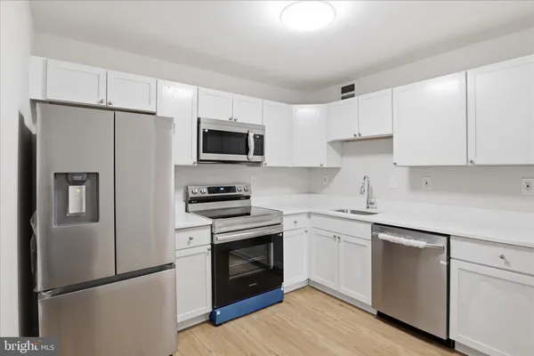 a kitchen with cabinets stainless steel appliances and a counter space
